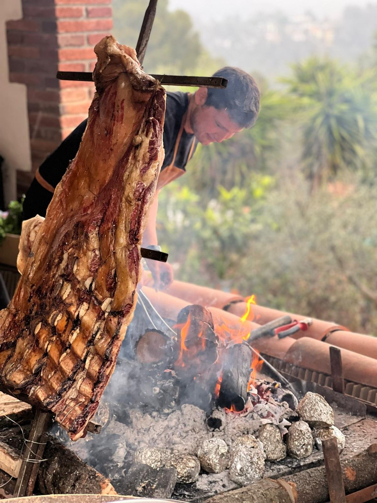 Alejandro levantando el costillar sobre el fuego